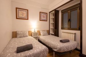 two beds in a small room with a window at San Sebastian Escape! in Loyola