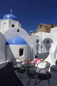 a table and chairs on a balcony with a church at Church and Cave - Santorini Private Residences in Mesaria