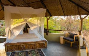 a bedroom with a canopy bed and a chair at Forsyth Lodge in Sohāgpur