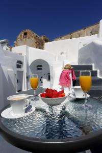 una mesa con un bol de fruta y dos vasos de zumo de naranja en Church and Cave - Santorini Private Residences en Mesariá