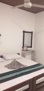 un letto in una stanza con uno specchio a parete di VILLA No34 HIKKADUWA a Hikkaduwa