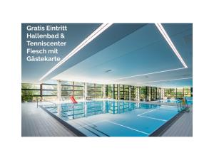a swimming pool in a building with glass windows at Bier & Erlebnis Hotel des alpes in Fiesch