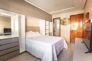 a bedroom with a white bed and a television at Apartamento a 200 metros da Praia do Cumbuco CE in Caucaia +19 photos