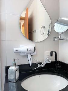 a bathroom sink with a hair dryer and a mirror at BarraVilha Resort Vista Mar e Pé na Areia in Barra Velha