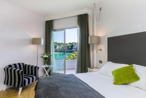 a hotel room with a bed and a chair and a window at ARTIEM Audax - Adults Only in Cala Galdana