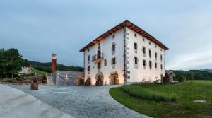 a large white building in a grassy field at Palacio de Yrisarri by IrriSarri Land in Igantzi