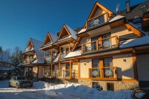 een groot gebouw met een auto in de sneeuw bij Apartamenty Pod Gubałówką in Zakopane