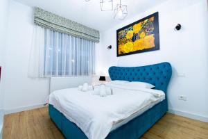 a bed with a blue headboard in a bedroom at Lighthouse Central Apt with unique views of the Fortress, Free Parking, 5 min by car from the Old Town in Braşov