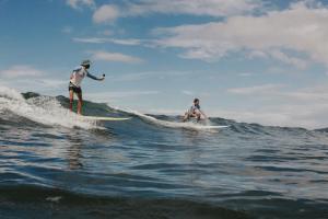 two men riding a wave on surfboards in the ocean at Surf Synergy All-Inclusive Surf Retreat in Jacó