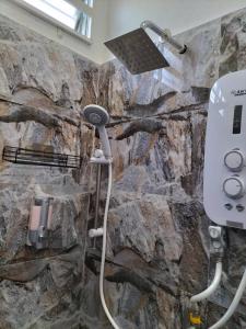 a shower in a bathroom with a stone wall at Wipah Guest House in Kampung Lundang, Kota Bharu in Kota Bharu