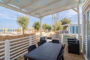 a table and chairs on a deck with a view of the beach at La Risacca Family Camping Village in Porto SantʼElpidio