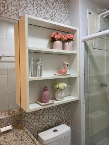 a bathroom with a toilet and vases on shelves at Muro Alto Clube Residence in Ipojuca