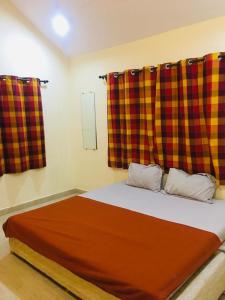 1 dormitorio con 1 cama con cortina de cuadros roja y amarilla en Bliss Villa 6Bhk Alibaug 1 Min Walking Distance To Kihim Beach en Alibaug