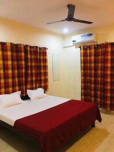 a bedroom with a bed with red and yellow curtains at Bliss Villa 6Bhk Alibaug 1 Min Walking Distance To Kihim Beach in Alibaug