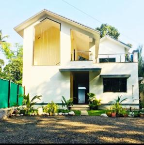 una casa blanca con una valla delante en Bliss Villa 6Bhk Alibaug 1 Min Walking Distance To Kihim Beach en Alibaug