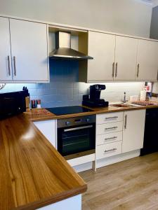 eine Küche mit weißen Schränken und einem Herd mit Backofen in der Unterkunft Merewyke Boutique Luxury Family Apartment Sleeps 4 , Central Location in Windermere