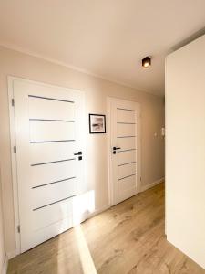 an empty room with white doors and wooden floors at Apartament IV piętro in Ustka