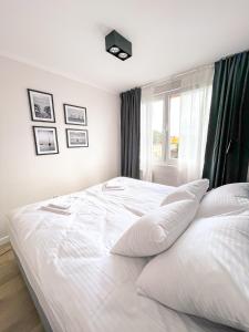 białe łóżko w sypialni z oknem w obiekcie Apartament IV piętro w Ustce
