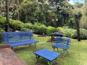 two blue benches and a grill in a park at Vale do Lajeado - Mountain chalets in Campos do Jordão