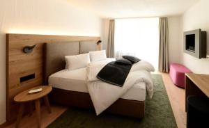 a bedroom with a bed with white sheets and a window at Hotel Bernina in Pontresina