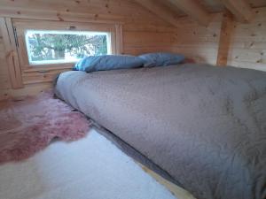 a bed in a log cabin with a window at Koobamäe saunamaja in Kulli
