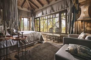 a bedroom with a bed and a couch and windows at Area Synest Nature Suites in Sinevrón