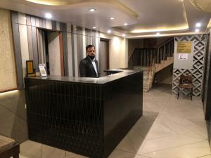 a man standing behind a counter in a lobby at Hotel Sweet Dream in Jaipur