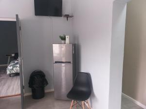 a silver refrigerator in a room with a black chair at TJ Self-catering in Graaff-Reinet