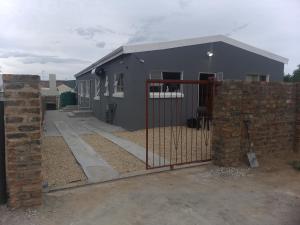 a fence in front of a house with a building at TJ Self-catering in Graaff-Reinet