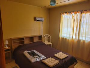 1 dormitorio con 1 cama con 2 toallas en Cabañas Palo Blanco en Gobernador Costa
