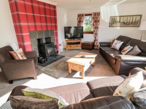 a living room with couches and a fireplace at Broombaulks Farm Bungalow in Jedburgh