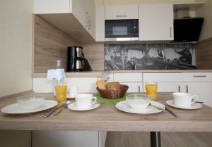 a kitchen counter with plates and glasses of orange juice at Appartementhaus Alt Büsum in Büsum