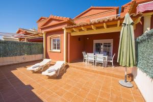 a patio with a umbrella and a table and chairs at Bungalow Java - Plusholidays in Calpe