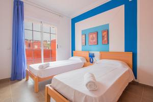 two beds in a room with blue walls and a window at Bungalow Java - Plusholidays in Calpe