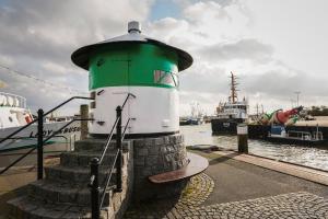 a green and white lighthouse sitting next to the water at Appartementhaus Alt Büsum in Büsum
