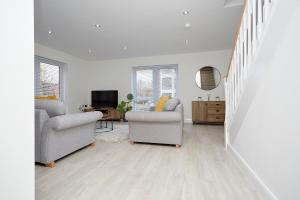 a white living room with two chairs and a tv at Luxury Duplex 2-Bed Apartment Fruit Market Marina in Hull