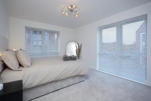 a white bedroom with a large bed with windows at Luxury Duplex 2-Bed Apartment Fruit Market Marina in Hull