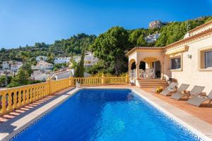 a swimming pool with chairs and a house at Villa Sabita - PlusHolidays in Calpe