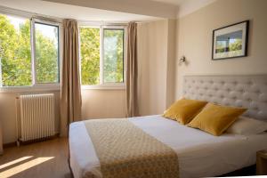 um quarto com uma cama e duas janelas em Hôtel Mondial em Perpignan