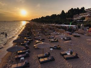 a beach with chairs and umbrellas and the ocean at Katrin Luxury Studios in Nea Moudania