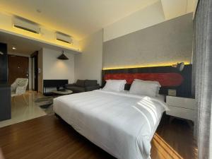 a bedroom with a large white bed and a living room at Ruby Apartment #4 in Kejayan