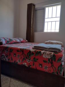 een slaapkamer met een bed met een rode deken en een raam bij Apartamento Avenida 01 in São Thomé das Letras