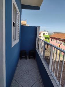 een balkon met 2 stoelen en een blauwe muur bij Apartamento Avenida 01 in São Thomé das Letras