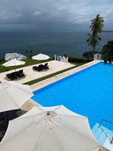 a swimming pool with white umbrellas and the ocean at Vista Mare Samana The Best View!! in Santa Bárbara de Samaná +55 photos