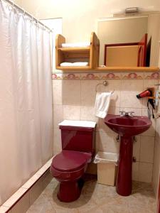 a bathroom with a red toilet and a sink at Hostal Quil in Guayaquil