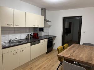 a kitchen with white cabinets and a wooden table at ARGENTA Living 42 in Künzell +76 photos