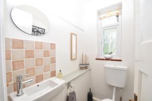 a bathroom with a sink and a toilet and a mirror at Maytham Cottage in Rye