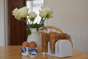 a table with eggs and a vase with flowers at Maytham Cottage in Rye