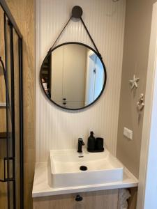 a bathroom with a white sink and a mirror at Baltic Apartment Posesja Kapitańska in Grzybowo