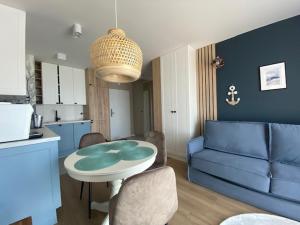 a living room with a table and a blue couch at Baltic Apartment Posesja Kapitańska in Grzybowo +11 photos